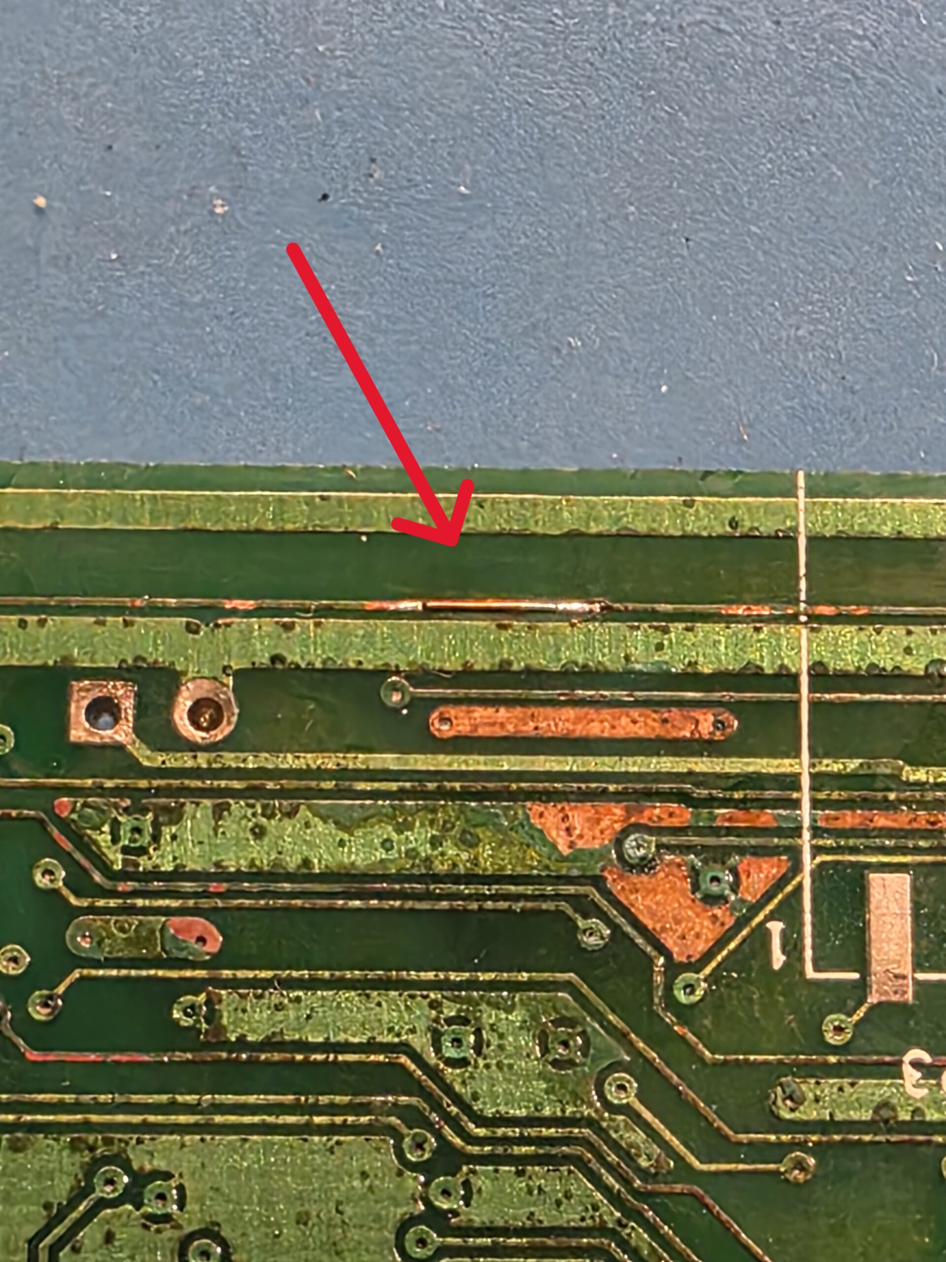 Microscopic PCB trace repair highlighted with red arrow